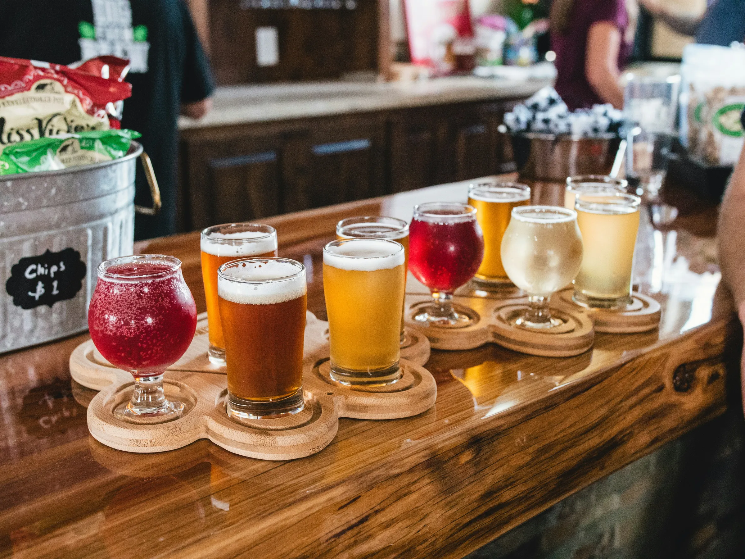 Flight of craft beers and ciders in tasting glasses on a wooden paddle at a brewery bar