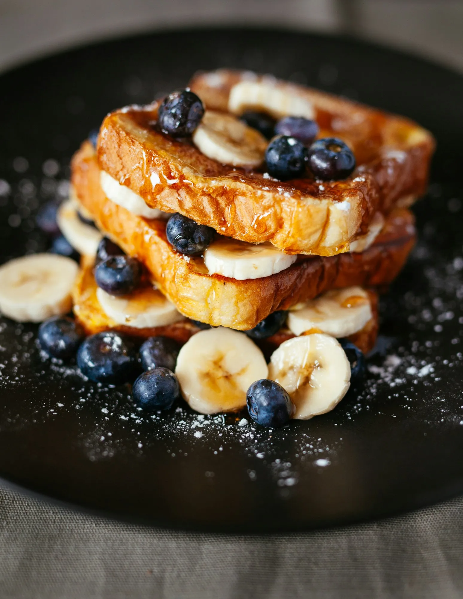 French toast stack with bananas, blueberries, syrup, and powdered sugar for a restaurant menu