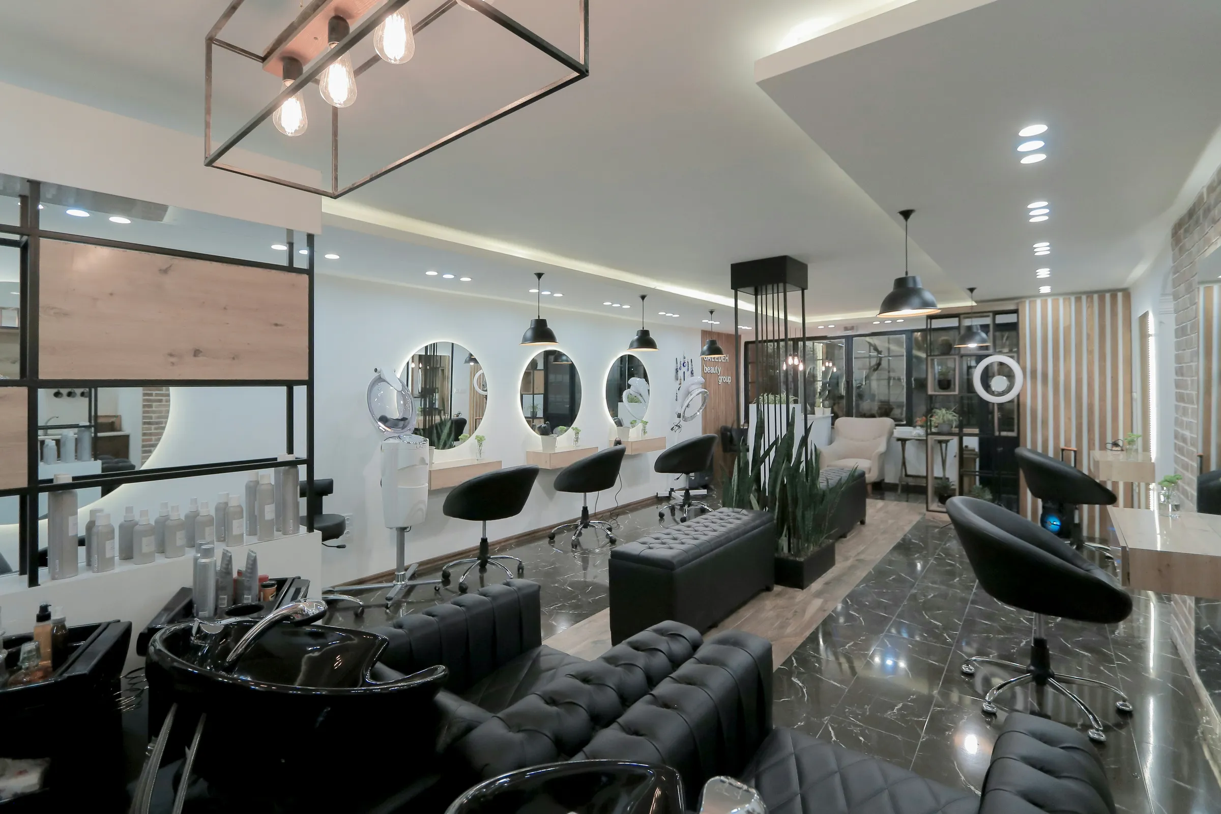 Modern salon interior with styling stations, round backlit mirrors, and black chairs