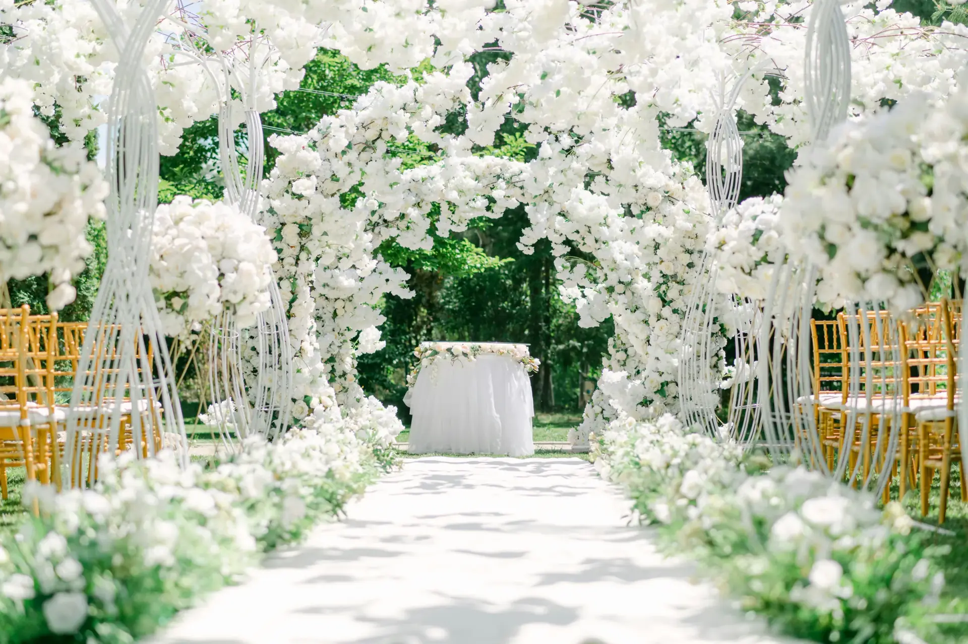 White floral arch over a wedding ceremony aisle