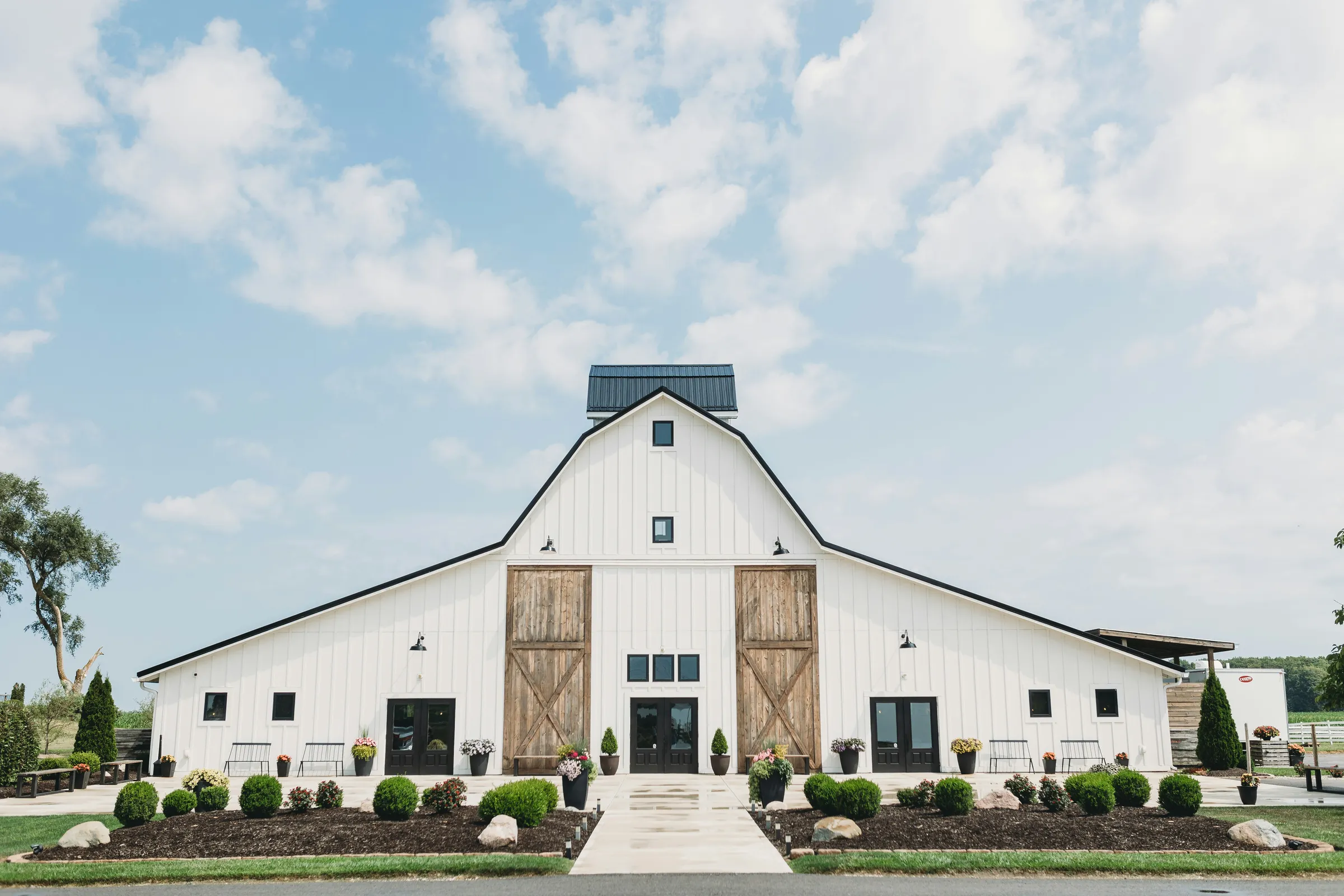 White barn wedding venue with wood sliding doors and a landscaped walkway entrance